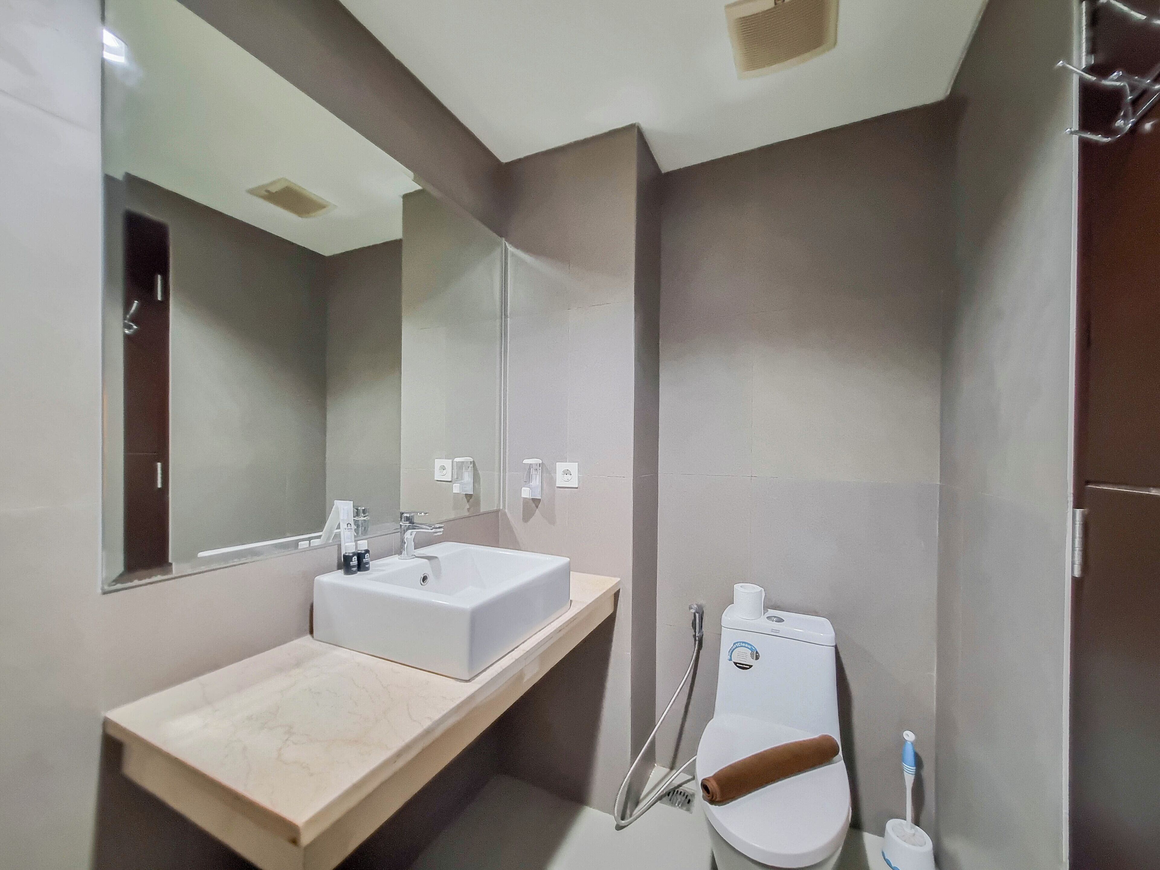 A modern bathroom with a large mirror, a sink, a toilet, and a shower area.