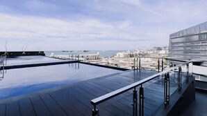 A rooftop terrace with a clear view of the sea and buildings in the distance. - The Simply Look 1Br Apartment At Delft Ciputra Makassar (Makassar)