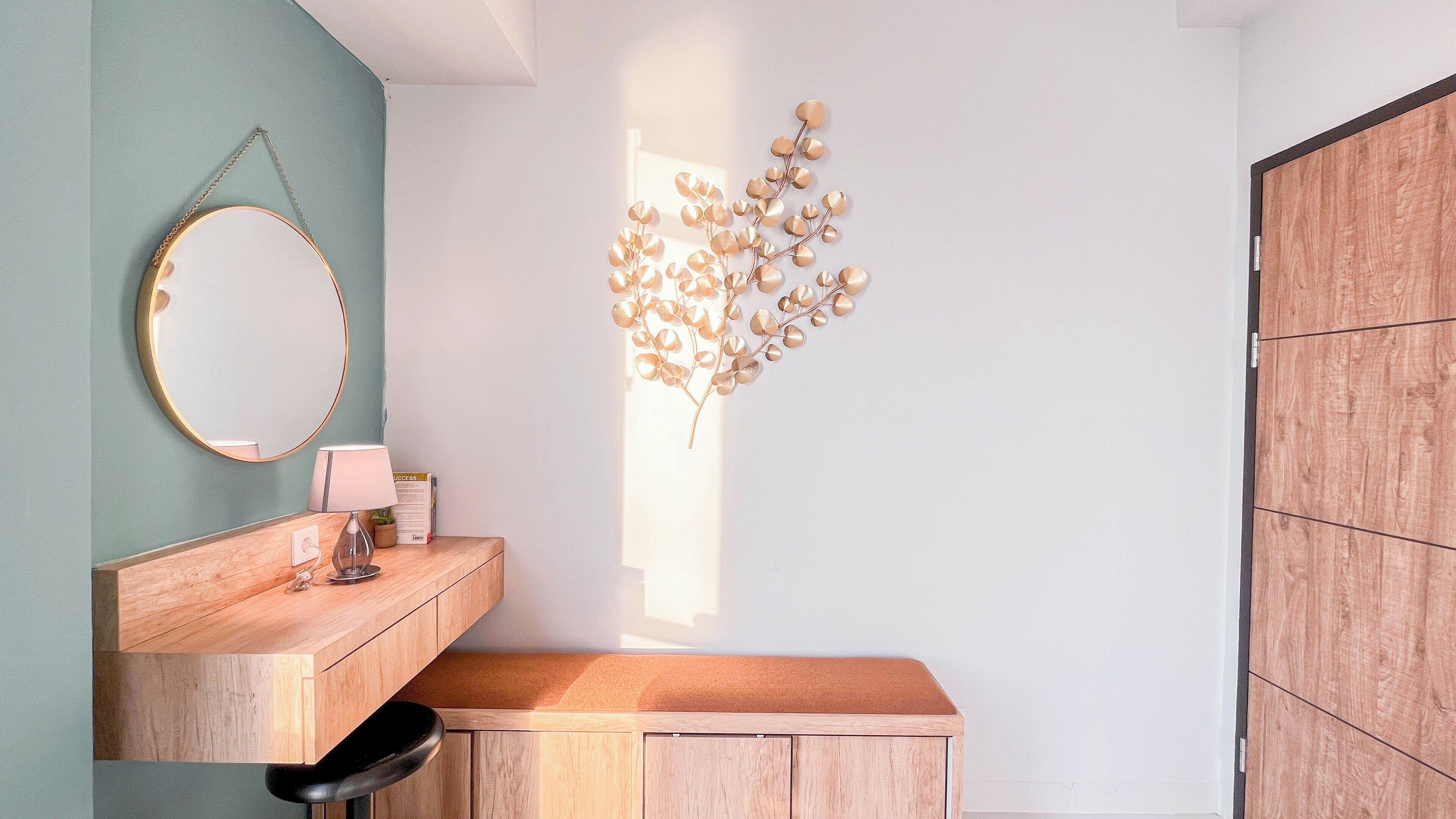 Een badkamer met een houten wastafelmeubel, een ronde spiegel, een wandlamp en een decoratieve plant.