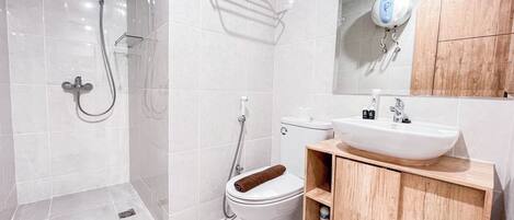 A modern bathroom with a glass shower enclosure, a toilet, and a sink with a wooden vanity.