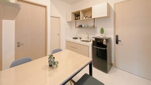 A compact kitchen with a dining table, a refrigerator, and built-in shelves. - Cozy Living 2Br Apartment Tokyo Riverside (Teluknaga)