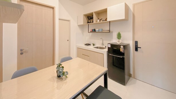 A compact kitchen with a dining table, a refrigerator, and built-in shelves. - Cozy Living 2Br Apartment Tokyo Riverside (Teluknaga)