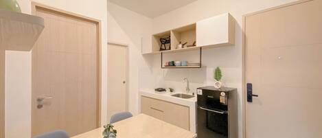 A compact kitchen with a dining table, a refrigerator, and built-in shelves.