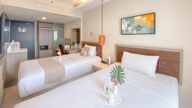 A hotel room with two beds, a large mirror, a painting, and a plant. - Comfy Studio (No Kitchen) At Apartment Grand Palace Kemayoran (Jakarta)