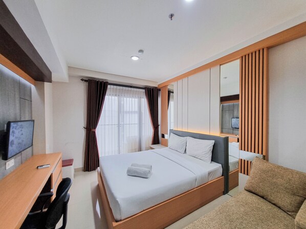 Une chambre d’hôtel avec un lit, un bureau, une chaise, une télévision et un miroir.