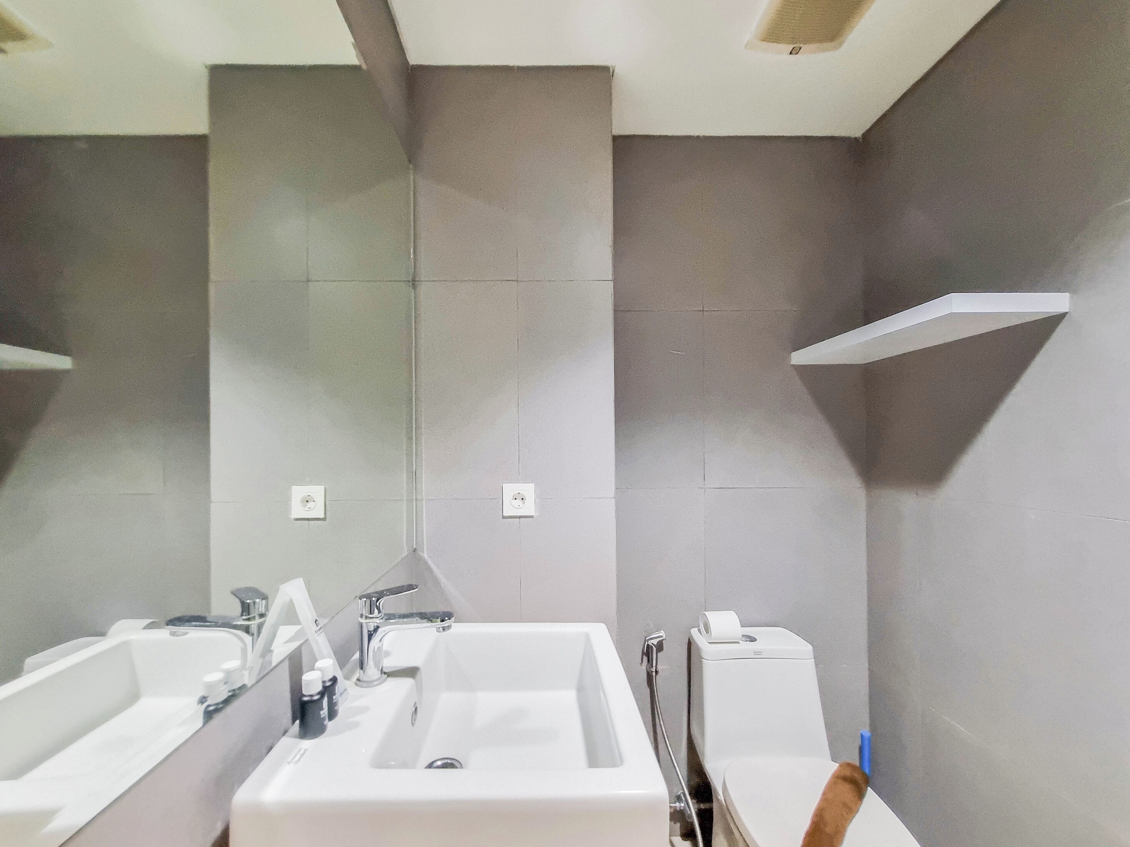A modern bathroom with a large sink, mirror, and toilet.