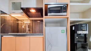 A compact kitchen with a microwave, refrigerator, and sink.