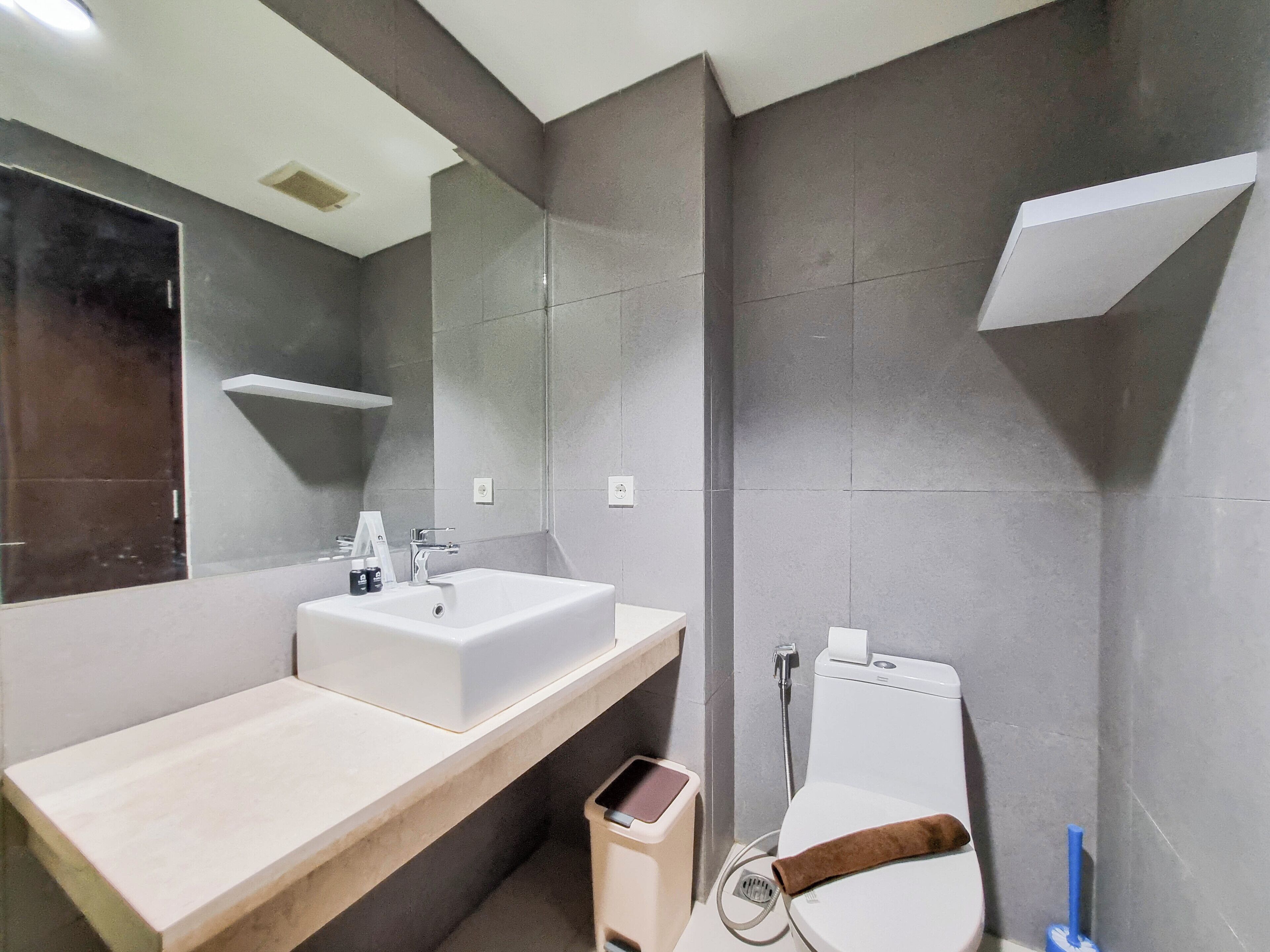 Un baño moderno con un espejo grande, un lavabo, un inodoro y una ducha.