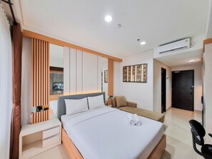 Una habitación de hotel moderna con una cama grande, un escritorio, una silla y un equipo de aire acondicionado.