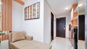 A modern bedroom with a bed, a sofa, a decorative wall panel, and a door.