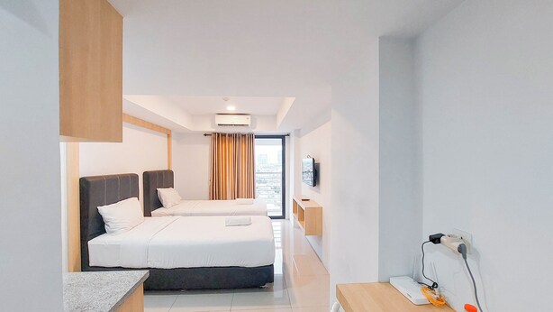 Habitación de hotel moderna con dos camas, televisión de pantalla plana y vista a la ciudad.