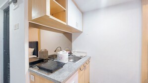 Una cocina compacta con estufa integrada, un lavamanos y armarios de madera.