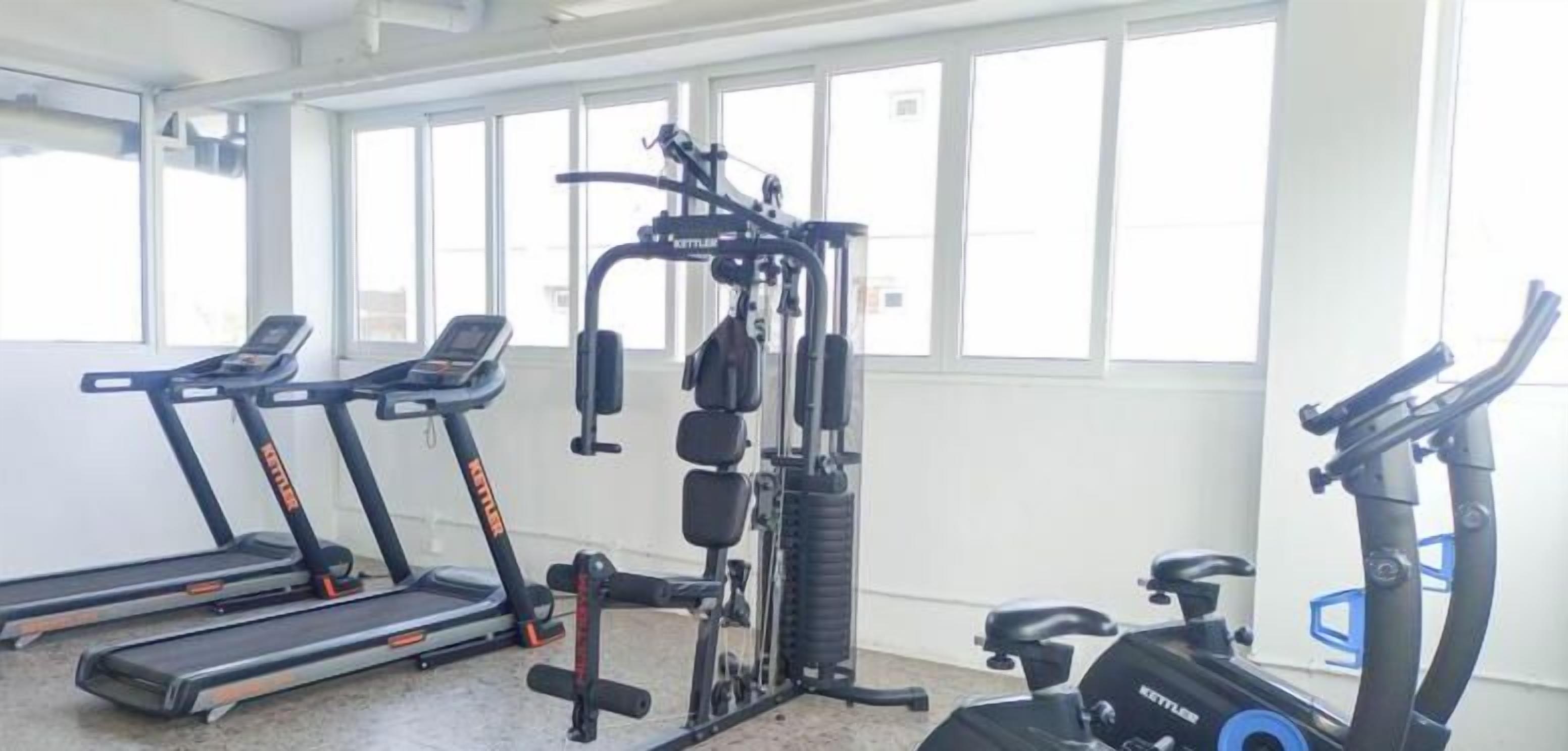 A gym with treadmills, a weight machine, and a stationary bike.