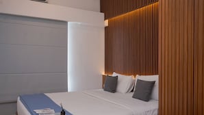 Una habitación de hotel moderna con una cama grande, cabecero de madera y una pared azul de acento.