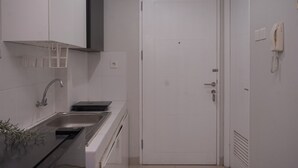 Een compacte, schone keuken met een spoelbak, kastjes en een deur.