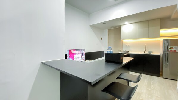 A modern kitchen with a bar area, a refrigerator, and a water dispenser. - Good And Homey 1Br At Tokyo Riverside Pik 2 Apartment (Teluknaga)
