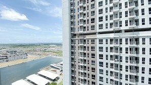 Un edificio de gran altura con múltiples balcones y vista a un río y un paisaje urbano distante.