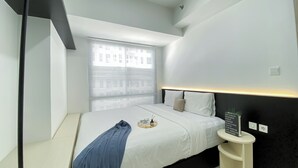 Una habitación de hotel moderna con cama, mesita de noche y ventana con persianas.