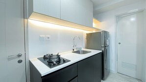 Una cocina moderna con estufa a gas, pileta de acero inoxidable y refrigerador empotrado.
