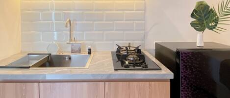 A modern kitchen with a white tiled backsplash, a stainless steel sink, a gas stove, and wooden cabinets.