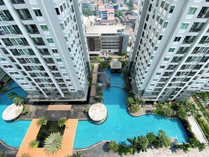 A high-rise building with a swimming pool and surrounding greenery. - Good Deal And Restful 1Br At Apartment Thamrin Residence (Jakarta)