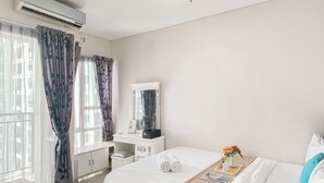 A hotel room with a bed, a vanity with a mirror, a desk, and a window with curtains. - Good Deal And Restful 1Br At Apartment Thamrin Residence (Jakarta)