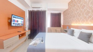Una habitación de hotel con cama, escritorio, televisión y cortinas.