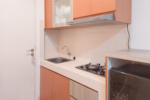 Compact kitchen area with stainless steel sink, gas stove, and microwave, perfect for a small living space.