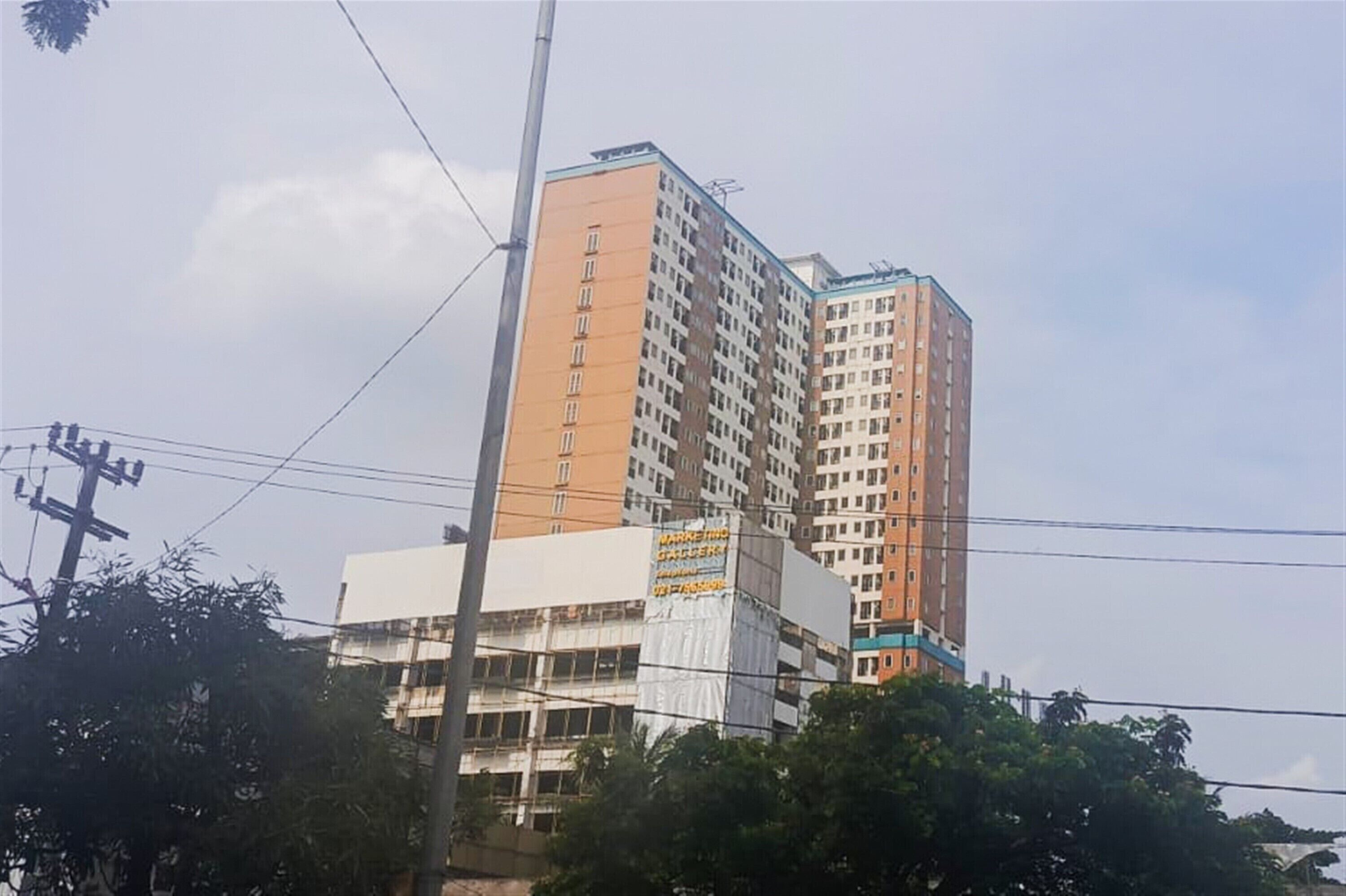 A multi-story building with a prominent orange and white facade, a visible sign for a market and guesthouse, and a partially constructed lower level.