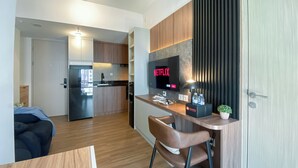 A modern kitchen with a built-in refrigerator, a dining area with a wooden table and chairs, and a TV displaying the Netflix logo. - Stunning And Spacious 1Br Apartment At Tokyo Riverside (Teluknaga)