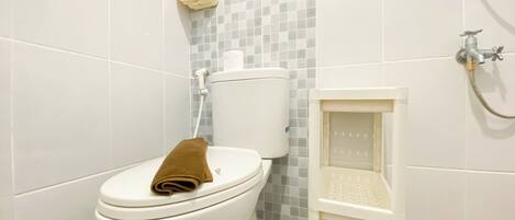 A bathroom with a toilet, a shower, and a hand dryer.