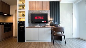 A modern kitchen with a built-in TV displaying 'NETFLIX', a water dispenser, and a dining area with a chair. - Stunning And Spacious 1Br Apartment At Tokyo Riverside (Teluknaga)