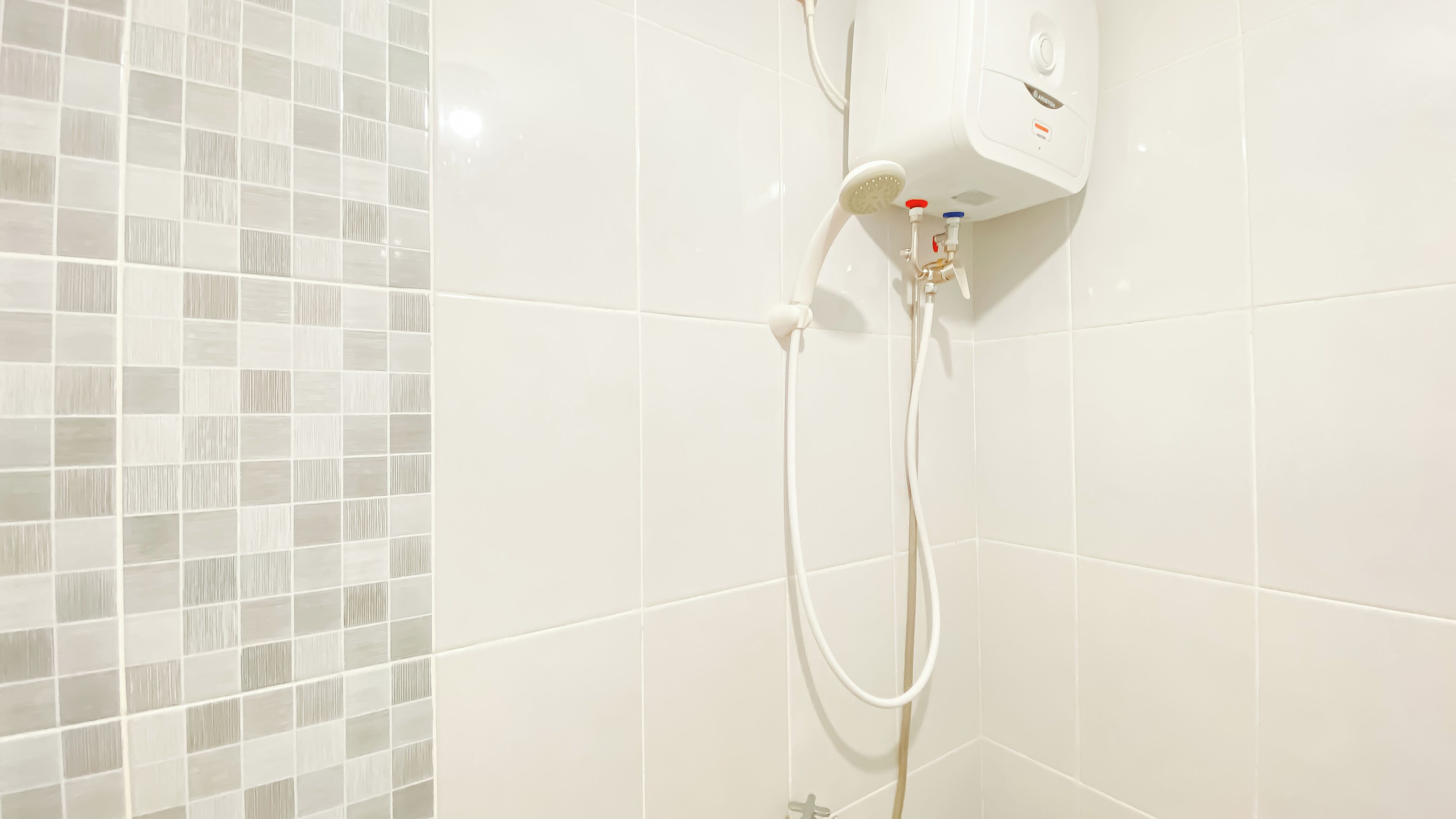 A bathroom with white tiled walls and a shower area.