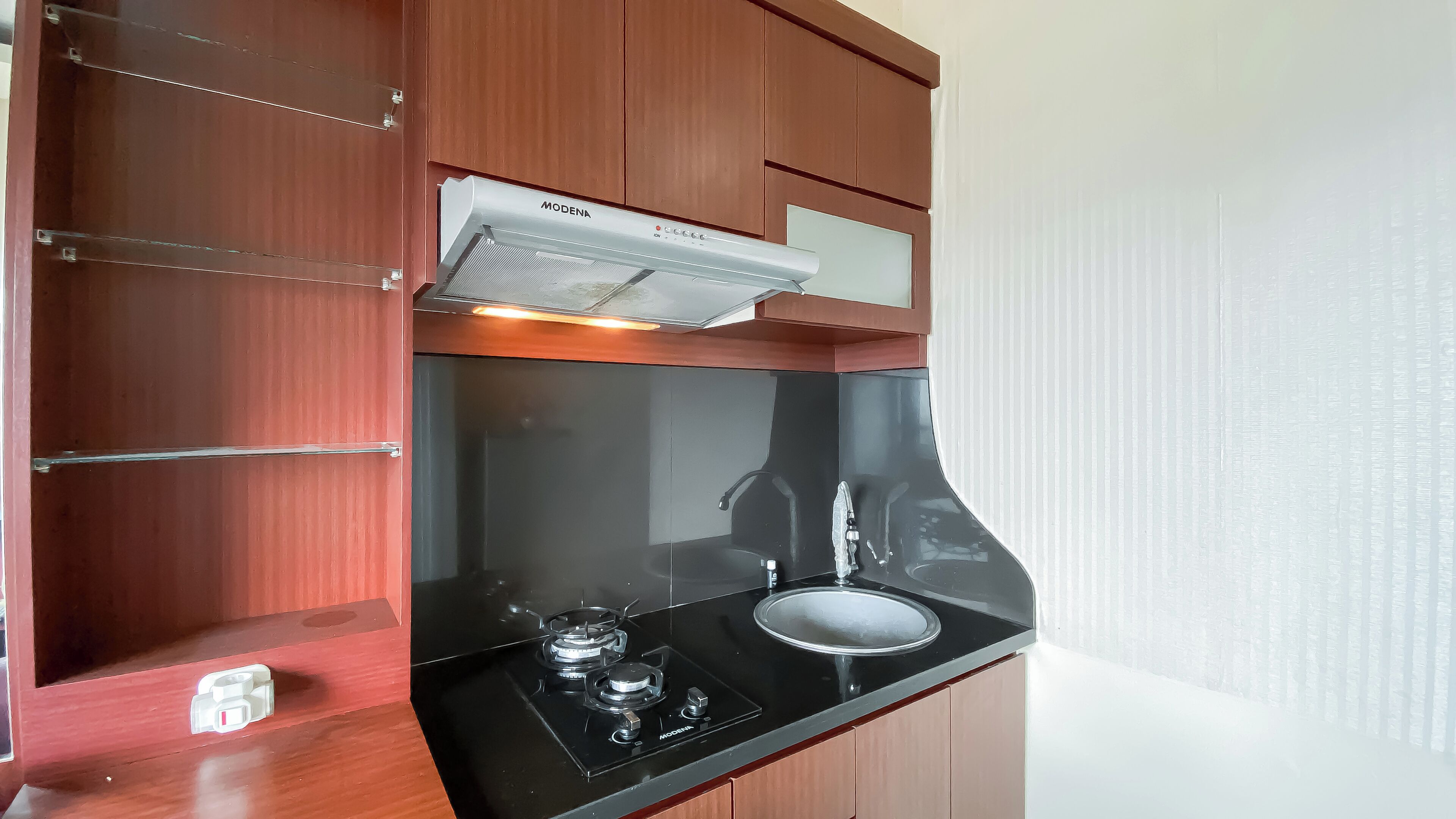 A kitchen with wooden cabinets, a black countertop, a gas stove, and a stainless steel sink.
