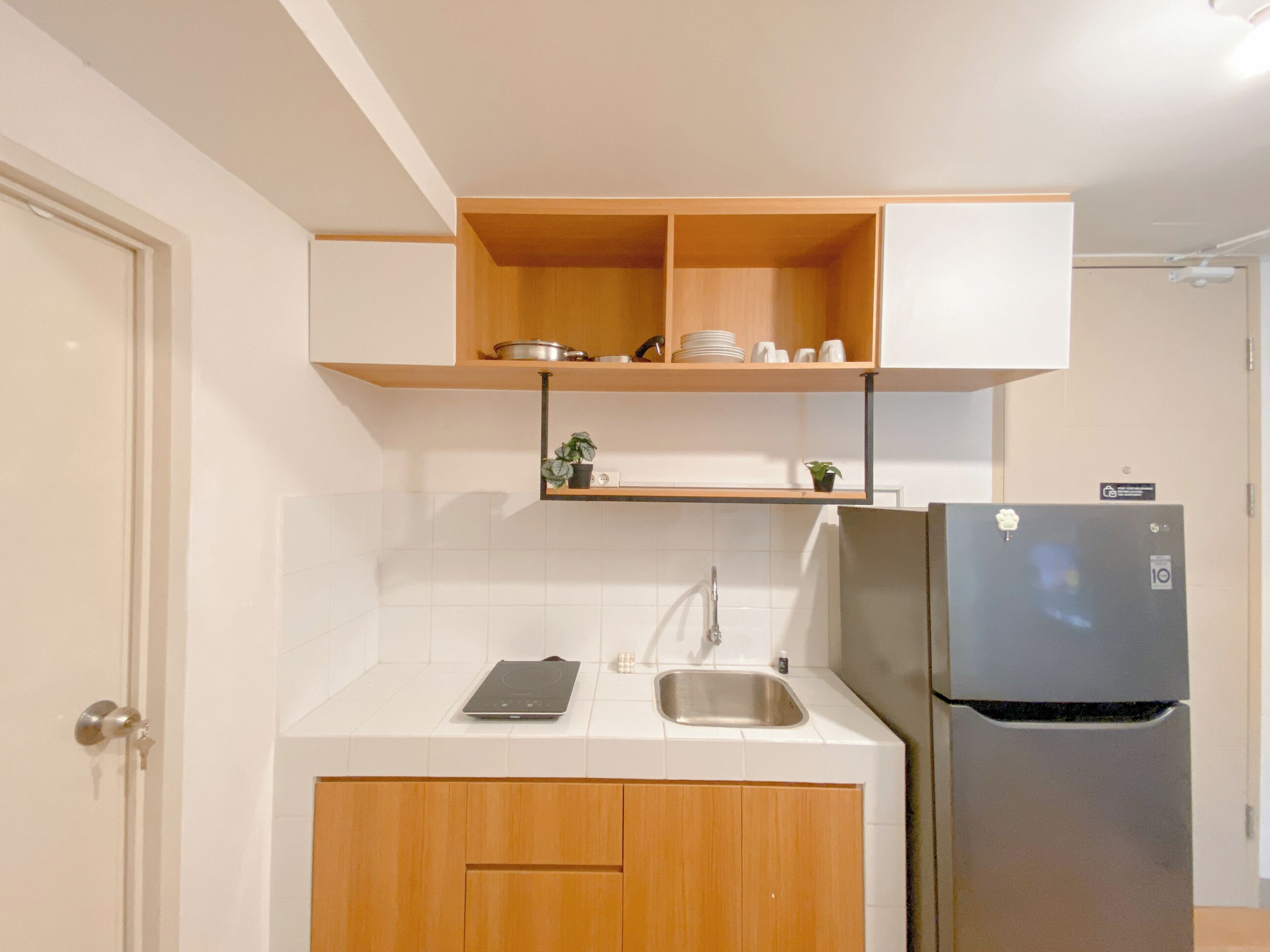 A modern kitchen with wooden cabinets, a built-in oven, a refrigerator, and a sink.