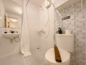 A bathroom with a shower, toilet, sink, and a sign prohibiting towels in the toilet. - Comfy 2Br Apartment At Tokyo Riverside (Teluknaga)
