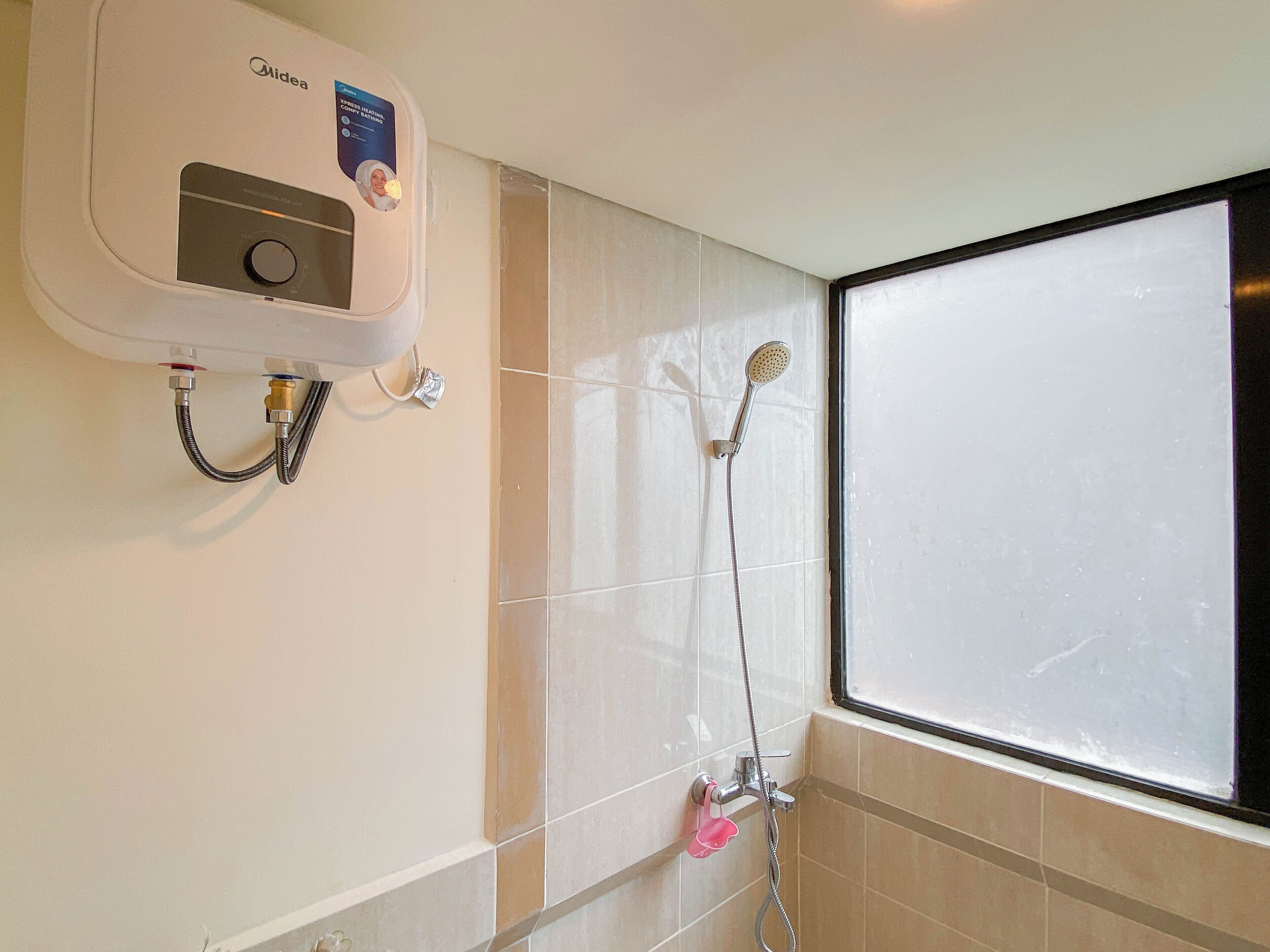 Ein Badezimmer mit einem Midea-Warmwasserbereiter, einer Dusche mit Duschbrausehandstück und einem Fenster.
