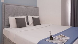 A neatly made bed with a grey headboard, white and grey pillows, and a blue throw blanket. - Comfortable And Strategic 2Br Apartment M-Town Residence (Gading Serpong)