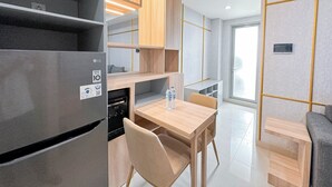 A modern kitchen with a built-in LG refrigerator, wooden cabinets, and a dining area with a table and chairs. - Elegant And Compact 1Br At Grand Sungkono Lagoon Apartment (Surabaya)