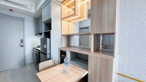 A modern kitchen with built-in appliances, a dining table, and a water dispenser. - Elegant And Compact 1Br At Grand Sungkono Lagoon Apartment (Surabaya)