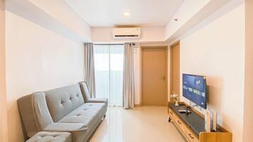 A modern living room with a grey sofa, a flat-screen TV, and a wooden cabinet.