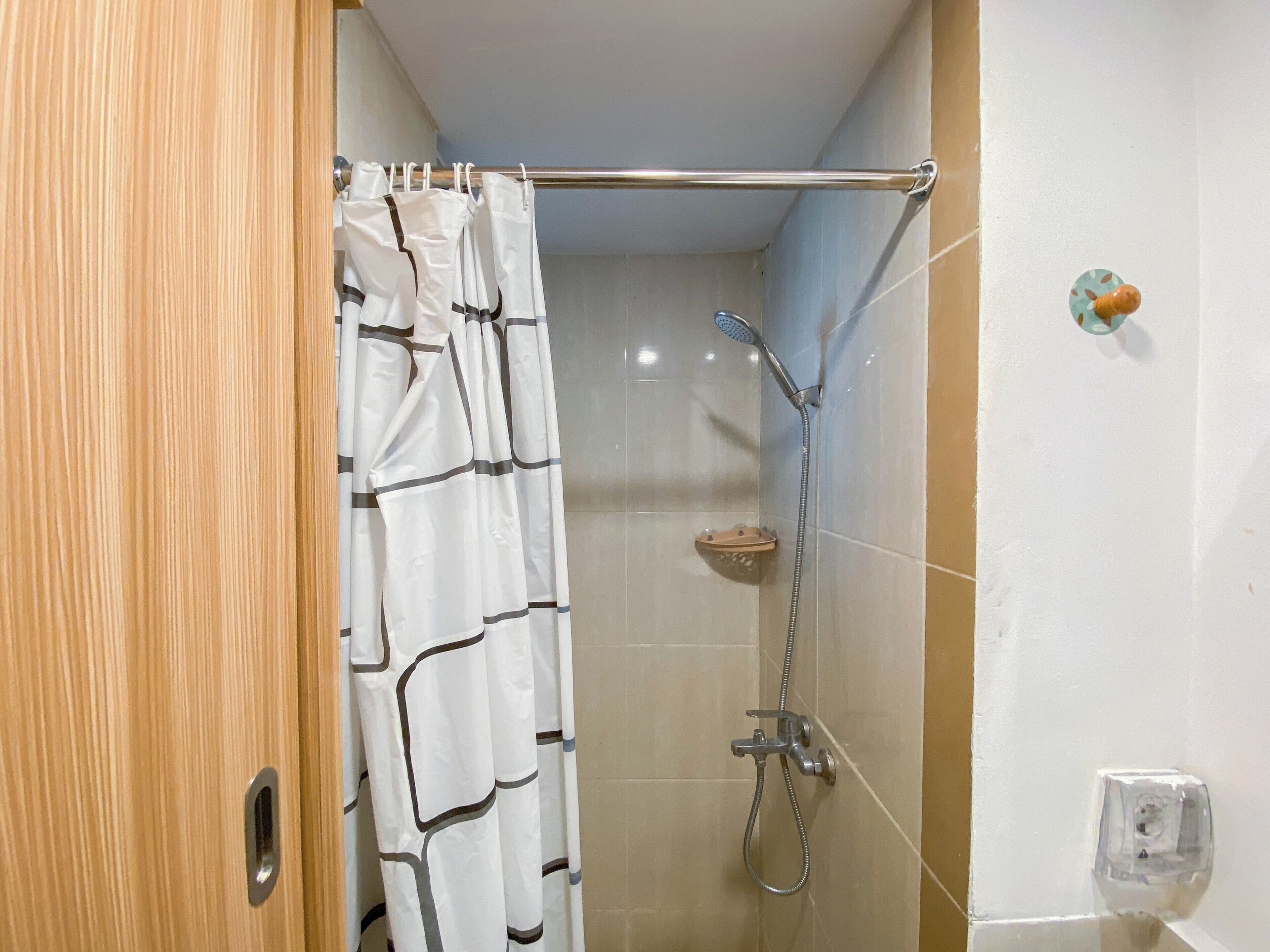 A shower area with a showerhead, a towel rack, and a shower caddy.