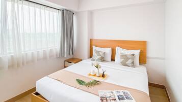 A hotel room with a bed, a nightstand, a window with curtains, and a bedside table with a tray of items.
