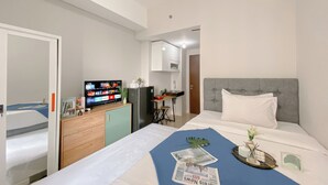 A hotel room with a bed, a television, a small kitchenette, and a bathroom. - Great Deal And Homey Studio Apartment At Transpark Juanda Bekasi Timur (Bekasi)