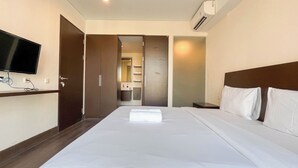 A hotel room with a bed, a TV, a wardrobe, and a bathroom visible through an open door. - Modern 2Br (No Kitchen) Apartment Skales Residence Nusa Dua Bali (Nusa Dua)