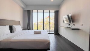 A hotel room with a large bed, a TV mounted on the wall, and a view of the outdoors through the window. - Comfort 2Br (No Kitchen) At Apartment Skales Residence Nusa Dua Bali (Nusa Dua)