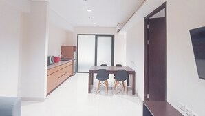 A modern kitchen with a dining area, white walls, and a flat-screen TV mounted on the wall. - Comfort 2Br (No Kitchen) At Apartment Skales Residence Nusa Dua Bali (Nusa Dua)