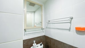 A bathroom with white and brown tiles, a glass shelf, a towel rack, and a soap dish. - Best Price And Relaxing 1Br At Green Pramuka City Apartment (Jakarta)