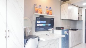 A modern kitchen with a marble countertop, a built-in TV, and a refrigerator. - Cozy And Homey Studio At Riverdale Apartment (Cikarang)