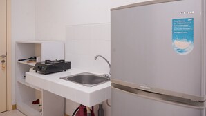 Una cocina compacta con encimera blanca, un lavamanos y un refrigerador Samsung.